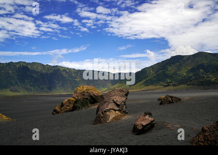 Mare di Sabbia nella valle di bromo con le montagne sullo sfondo e cielo blu nel mattino di Tengger Semeru National Park in Java Orientale, Indonesia. Foto Stock