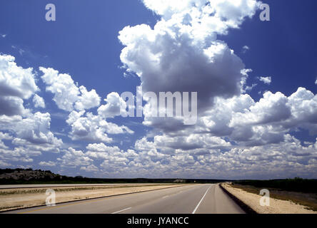 Nuvole blu cielo cielo e terra Ampia angolazione del brillante cumulous celesti nuvole che pende sulla autostrada vuota all orizzonte strada aperta© Myrleen Pearson Foto Stock