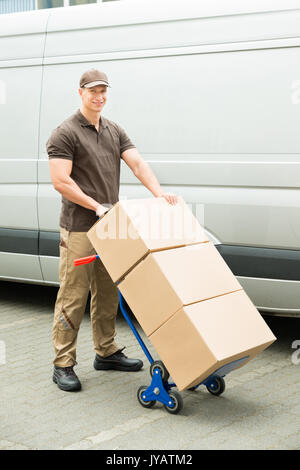 Giovane uomo di consegna Azienda Carrello con scatole di cartone Foto Stock