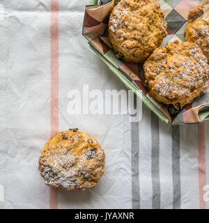 Home fatta di uvetta scones su un tavolo decorato panno. Vista dall'alto. Formato squadrato. Foto Stock