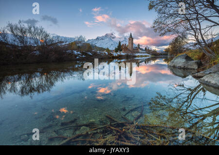 Alba illumina le vette innevate e la torre campanaria si riflette nel lago di Sils Engadina Canton Grigioni Svizzera Europa Foto Stock