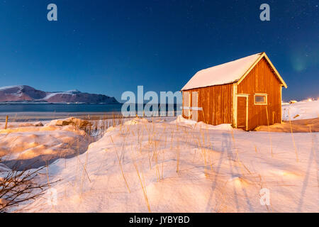 Luna su una tipica cabina di pescatori circondato da neve Flakstad Ramberg Nordland County Lofoten in Norvegia Europa Foto Stock