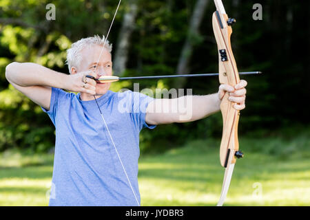 Atleta maschio mirando con arco e frecce nella foresta Foto Stock