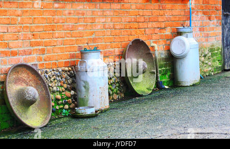 Agriturismo roba. Metallo bidoni di latte su un muro di mattoni, England Regno Unito. Vecchio e vintage prodotto caseario latte settore alluminio può serbatoio. Foto Stock
