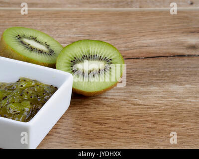 Marmellata di kiwi e kiwi su uno sfondo di legno Foto Stock