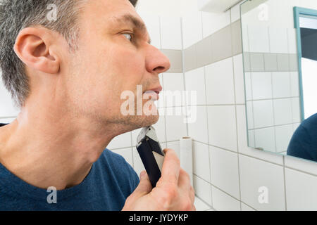 Ritratto di un uomo in cerca di rifinitura a specchio barba Foto Stock