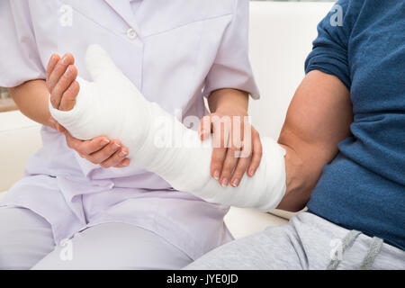 Close-up di un medico donna Holding si è fratturato la mano di un paziente Foto Stock