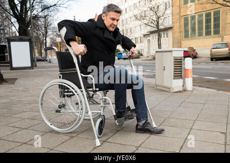 Disabilitato L'uomo cercando di camminare con l'aiuto stampelle Foto Stock