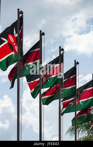Una fila di bandiere keniano su pali sventolare nel vento in una giornata di sole, Nairobi, Kenia Foto Stock
