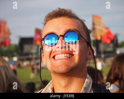 UK - 22 Giugno, 2017: Un uomo sorridente e felice in un festival musicale che indossa occhiali da sole Foto Stock