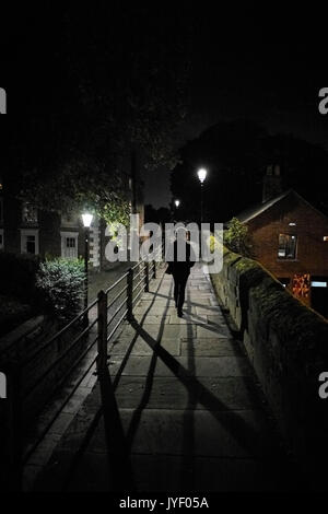 La donna a piedi dalla fotocamera alla notte in città Foto Stock