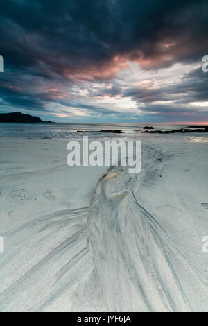 Il sole di mezzanotte e le nuvole cornice alla spiaggia sabbiosa di Flakstad Skagsanden Nordland county Isole Lofoten in Norvegia Europa Foto Stock