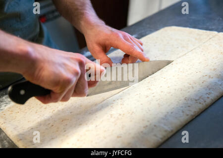 Uno chef che taglia la pasta per la produzione di grissini italiano Foto Stock