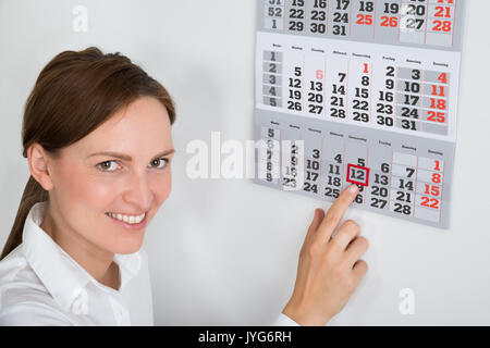 Close-up di giovane imprenditrice immissione contrassegno rosso sulla data di calendario Foto Stock