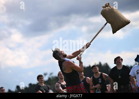 Horgenzell, Germania. 19 Ago, 2017. Un partecipante della tomaia Highlandgames sveva getta un sacco di fieno con una forcella di passo attraverso un ostacolo nella disciplina 'Sheaf Toss' in Horgenzell, Germania, 19 agosto 2017. 15 clan competere gli uni contro gli altri in varie discipline al Highlandgames. Foto: Karl-Josef Hildenbrand/dpa/Alamy Live News Foto Stock