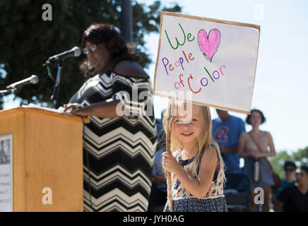 Gianna Whitehawk di Buda, TX detiene un segno come attivisti e manifestanti convergono sul Municipio per un caldo due ore di rally contro il razzismo e la presidente Donald Trump's evidenti insensibile commenti sulle recenti Charlottesville e la violenza che ha lasciato un morto. Circa mille raccolti nel mese di agosto il Texas calore. Foto Stock