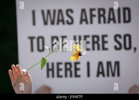 Vancouver, Canada. 19 Ago, 2017. Un protestor può contenere fino a un fiore di fronte un segno durante un anti-razzismo rally al di fuori di Vancouver City Hall a Vancouver, Canada, 19 Agosto, 2017. Credito: Liang Sen/Xinhua/Alamy Live News Foto Stock