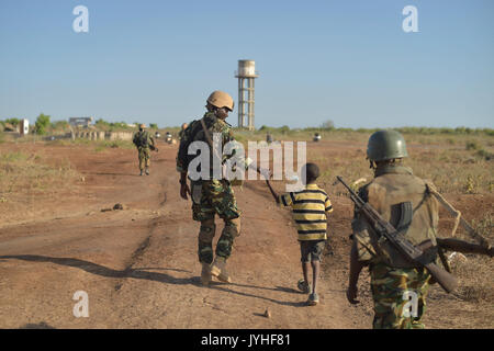 Un soldato del Burundi, come parte della missione dell Unione Africana in Somalia, detiene un giovane ragazzo in mano vicino la città di Mahaday, Somalia, durante una pattuglia. AMISOM Foto Tobin Jones (27447000731) Foto Stock