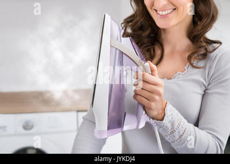 Close-up di Donna sorridente Tenendo Ferro da stiro a vapore in mani Foto Stock