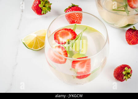 Estate cocktail rinfrescante. La limonata con calce, fragole fresche e rosmarino. Su un marmo bianco tavola. Spazio di copia Foto Stock