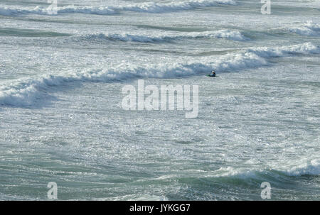 Una solitaria in kayak o paddler kayaker nel mare e surf a polzeath in Cornovaglia a nord della Cornovaglia costa atlantica sul suo proprio su una ruvida e tempestoso giorno Foto Stock