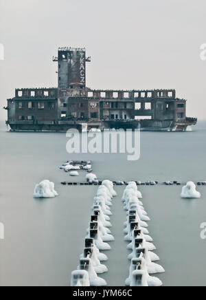 Tappi di ghiaccio su vecchi paletti di legno in linea e le rovine del palazzo a siluro Foto Stock