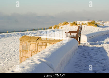 Vista laterale di un banco a Exmouth beach, coperto di neve si insediarono Foto Stock