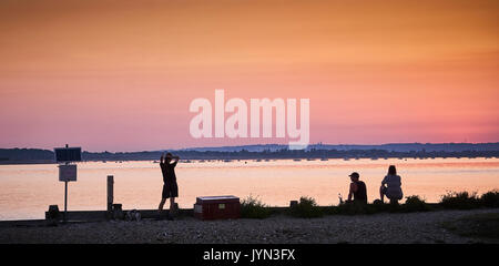 La gente guarda un tramonto sul West Wittering spiaggia, porto di Chichester, Sussex Foto Stock