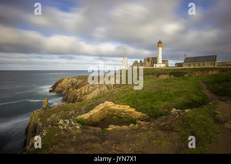 Il Lighthouse e abbey salire al di sopra del mare e coste rocciose a Pointe Saint-Mathieu in Bretagna, Francia Foto Stock