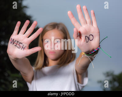 Ragazza adolescente tenere mani con citazioni motivazionali scritto su palme. Foto Stock