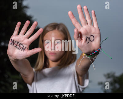 Ragazza adolescente tenere mani con citazioni motivazionali scritto su palme. Foto Stock