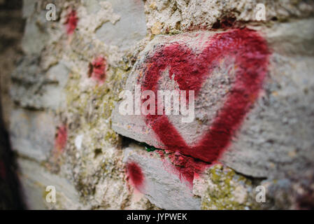 Close up graffiti di sfondo silhouette di un cuore rosso su un rilievo vecchio muro di pietra. Foto Stock