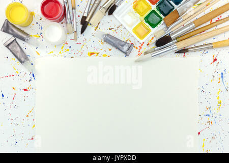 Pennelli tavolozza, vernici ad acquerello e foglio di carta bianca sulla scrivania dell'artista Foto Stock
