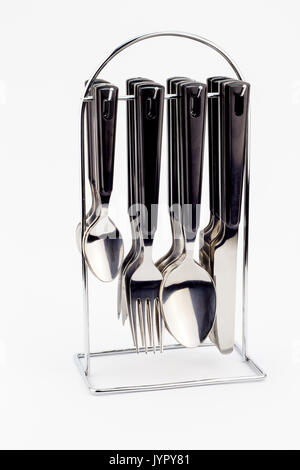 Coltelli e forchette e cucchiai con maniglie nere appeso su di un supporto in metallo isolato su sfondo bianco Foto Stock