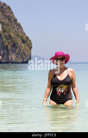 Senior donna che indossa cappello rosa in mare, Koh Lao Liang, Trang, Thailandia Foto Stock