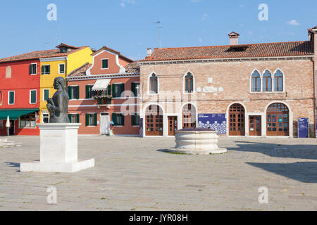 Maggio 2017. Isola di Burano, Venezia, Italia. Vista della piazza Galuppi con il museo del merletto e case colorate e un ristorante. In primo piano è un st Foto Stock