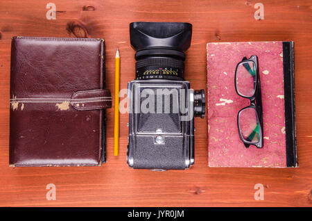 Hipster attrezzature, vecchia agenda, vecchio libro, vecchia macchina fotografica, matita, occhiali su sfondo di legno Foto Stock