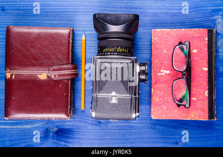 Hipster attrezzature, vecchia agenda, vecchio libro, vecchia macchina fotografica, matita, occhiali su sfondo di legno Foto Stock