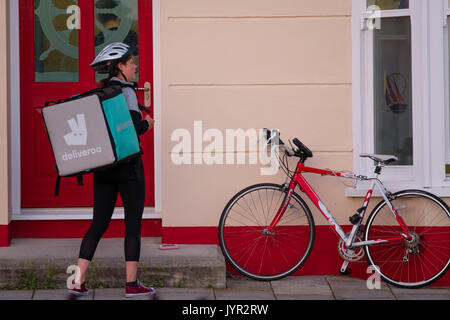 La gig ECONOMIA NEL REGNO UNITO: un giovane lavoratore autonomo donna ragazza con la bicicletta per lavoro Deliveroo, la cucina take away società di consegna Foto Stock