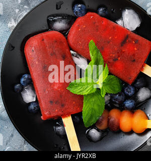 Frutto di ghiaccio da cocomero, arancione e mirtilli con foglie di menta. Vista superiore del dessert estivo Foto Stock