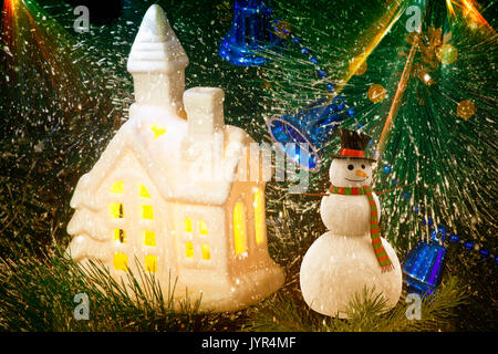Addobbi per albero di Natale: bella casa bianca con Windows giallo brillante luce e Blue Bells. Presenta su un albero di Natale. Foto Stock