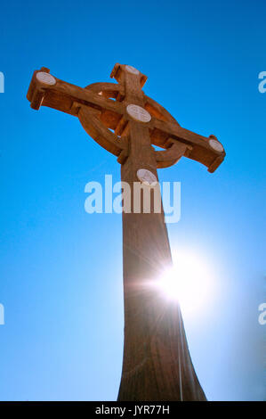 Benedettino croce di legno con sunbeam sostenuto dal blu intenso del cielo. Foto Stock