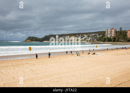 Surfers e altra gente sulla spiaggia di Manly su un soleggiato inverni giorno, Sydney, Australia Foto Stock