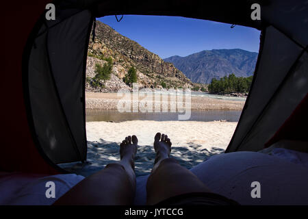 Vista dalla tenda turistico interno sulla montagna paesaggio con fiume. womans gambe in montagna Foto Stock