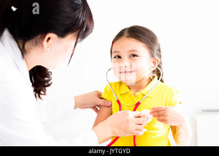 Medico donna esaminando bambina da uno stetoscopio Foto Stock