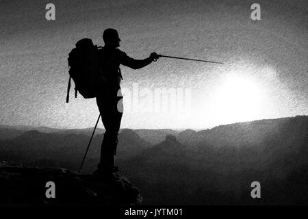 Bianco e Nero tratteggiato schizzo retrò. Sharp silhouette di un uomo alto sulla cima della montagna con Sun nel telaio Foto Stock