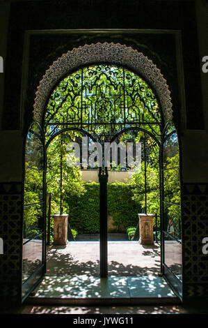 Spagna: Giardini dell'Alcazar di Siviglia, il royal palace eccezionale esempio di architettura mudejar, visto attraverso una in ferro battuto della porta di prua Foto Stock