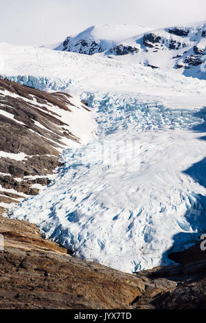 Engabreen o Enga braccio del ghiacciaio di Svartisen calotta di ghiaccio con la gente che camminava sulle rocce per mostrare la scala. Saltfjellet-Svartisen National Park, Norvegia Foto Stock