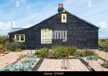 Prospettiva Cottage, la casa e il giardino del film maker Derek Jarman su Dungeness. Il poema sulla parete di estremità è il sorgere del sole da John Donne. Foto Stock