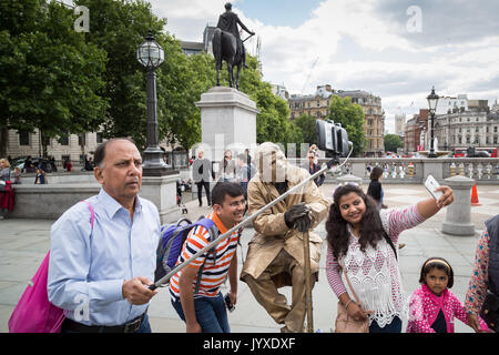 Londra, Regno Unito. 20 Agosto, 2017. I turisti scattare foto e telefono selfies con un oro statua umana in Trafalgar Square. Credito: Guy Corbishley/Alamy Live News Foto Stock